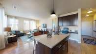 Located at 1724 Steel St in Louisville, Colorado, this single-floor residence offers a thoughtfully designed open-concept layout that seamlessly connects the kitchen, dining, and living areas. The kitchen is a standout feature, showcasing rich dark cabinetry, granite countertops, stainless steel appliances including a full-size refrigerator, a black range and microwave, and a central island with bar seating — all illuminated by track lighting and a stylish pendant fixture. Hardwood flooring flows throughout the main living areas, adding warmth and continuity to the space. The living room is bathed in natural light from multiple large windows dressed with sheer curtains and blinds, creating a bright and welcoming atmosphere. A dedicated workspace area is conveniently integrated into the open layout. The bedrooms feature plush carpeting, generous natural light, and walk-in closets with built-in shelving. One bedroom is accented by a bold teal feature wall, adding a vibrant, personalized touch. The bathrooms are finished with clean tile work, including a full tub-shower combination. A private entry door leads directly to an outdoor area, providing easy access and added convenience. The overall design balances modern aesthetics with functional, comfortable living.
