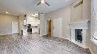 Located on Summitry Circle in Katy, TX, this single-floor residence offers a thoughtfully designed layout with a clean, modern aesthetic throughout. The open-concept living area is a standout feature, anchored by a classic white-mantled fireplace and adorned with wood-style plank flooring that extends throughout the main living spaces. Large windows with blinds invite abundant natural light, offering pleasant views of the surrounding greenery, while a ceiling fan adds to the comfort of the room.

The kitchen is well-appointed with white shaker-style cabinetry, light countertops, a subway tile backsplash, and a full suite of stainless steel appliances including a refrigerator, range, microwave, and dishwasher. The layout connects seamlessly to the living area, making it ideal for everyday living.

The bedrooms feature plush carpeting and generous windows that bring in natural light. The primary bedroom provides direct access to an en-suite bathroom, which includes a wide white vanity with ample cabinet storage, a large mirror, and a shower-tub combination. A second full bathroom mirrors the same clean, bright design with matching white cabinetry and hardwood-style flooring. The overall palette of warm neutrals and white trim creates a cohesive and inviting atmosphere throughout the home.