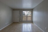 Located at 2402 Bammelwood Dr in Houston, Texas, this single-story home offers a straightforward and functional layout spread across a well-organized floor plan. The interior is finished with light-toned ceramic tile flooring throughout, providing a cohesive and easy-to-maintain surface across all living areas.

The entry leads into a bright living area featuring a front-facing window with blinds that allows natural light to fill the space. Neutral gray walls and white baseboards give the interior a clean, understated appearance. A ceiling fan with an integrated light fixture is present in one of the rooms, offering both air circulation and overhead lighting.

The kitchen is equipped with a black electric coil range, a refrigerator with top-mounted freezer, a range hood, and tile backsplash. A pass-through counter connects the kitchen to the adjacent living or dining area, enhancing the sense of openness between spaces. White cabinetry and a utility sink complete the kitchen setup.

The bathroom features a full tub and shower combination enclosed by floor-to-ceiling neutral beige tile, complemented by chrome fixtures. Additional rooms are generously sized with tile flooring and neutral wall finishes, offering flexible use as bedrooms or secondary living spaces. The overall ambiance of the home is clean, practical, and move-in ready.