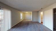 This two-story residence offers a functional and well-organized layout across two floors, featuring two bedrooms, two full bathrooms, and a half bath. The living area is generously sized, with plush carpeting, neutral gray walls, a textured ceiling, and a sliding glass door that allows natural light to filter in alongside a large window — creating a bright, open atmosphere.

The kitchen is equipped with white cabinetry, a coil-burner electric range, a full-size refrigerator, a range hood, and hardwood-style flooring, providing a clean and efficient cooking space. A half bathroom on the main level adds everyday convenience, also featuring hardwood-style flooring and white fixtures.

Both bedrooms are carpeted and feature ceiling fans with integrated lighting, neutral walls, and built-in closets with shelving and hanging rods for ample storage. One bedroom includes a spacious sliding-door closet, while the other offers an open-style built-in closet.

Each full bathroom includes a tub-shower combination, white vanity cabinetry with granite-style countertops, and hardwood-style flooring. Textured ceilings are consistent throughout the home, contributing to a cohesive and understated aesthetic across all rooms.