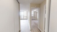 Located on the 22nd floor of 555 Sherbourne Street in Toronto, this one-bedroom, one-bathroom unit offers a well-organized layout across a single floor, comprising a living room, bedroom, kitchen, bathroom, and hallway. Light-toned hardwood flooring runs throughout, complementing the neutral warm-beige walls and white trim to create a bright, cohesive aesthetic. The living room is a standout space, featuring floor-to-ceiling sliding glass doors that open onto a private balcony, filling the room with natural light and offering sweeping views of the Toronto skyline and surrounding neighbourhood. The kitchen has been thoughtfully updated with crisp white shaker-style cabinetry, sleek brushed-nickel hardware, marble-look countertops, a white subway tile backsplash, and a stainless steel range — delivering a clean, contemporary finish. The bedroom is a comfortable retreat with a large window that brings in additional natural light and an urban view, alongside a built-in closet with sliding panel doors. A textured ceiling adds subtle character throughout the unit. The bathroom features a full soaking tub with an overhead shower, white tile surround, and clean, functional fixtures. The hallway connects all rooms efficiently, making the most of the unit's compact yet practical footprint.