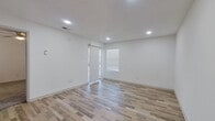 This single-floor, one-bedroom, one-bathroom unit offers a clean, modern interior designed for efficient use of space. The combined kitchen and living area forms the heart of the unit, finished with light-toned wood-look plank flooring throughout. Recessed lighting illuminates the living space, which receives natural light through a sliding glass door fitted with vertical blinds, providing both outdoor access and brightness.

The galley-style kitchen is outfitted with dark navy cabinetry on both upper and lower levels, white countertops, a stainless steel sink, a black electric range, and a dishwasher. The layout maximizes counter and storage space within a compact footprint.

The bedroom is carpeted and benefits from a large window with blinds, allowing natural light to fill the room. A dedicated closet with a hanging rod provides organized storage. The bathroom is conveniently accessible from the bedroom area and features dark cabinetry with a vanity, a well-lit mirror, and a walk-in shower with clean white surrounds and wood-look flooring.

Throughout the unit, white walls and clean finishes create a bright, neutral aesthetic that feels open and easy to personalize.