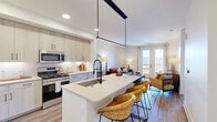 Located in Colorado Springs, CO, this thoughtfully designed one-bedroom, one-bathroom residence offers a seamless blend of modern style and functional living. The open-concept layout connects the kitchen, dining, and living areas into a cohesive, light-filled space anchored by durable wood-look flooring throughout. The kitchen is a standout feature, boasting light wood cabinetry extending to the ceiling, a herringbone tile backsplash, stainless steel appliances including a gas range and French door refrigerator, and a central island with a waterfall-edge countertop and woven bar seating — ideal for casual dining or entertaining. A bold linear pendant light adds a modern focal point overhead. The living room opens directly to a private balcony through elegant French doors, framing sweeping mountain views that bring the Colorado landscape indoors. The bedroom is a serene retreat highlighted by a dramatic slatted wood accent wall, large windows with mountain vistas, and a ceiling fan. The bathroom features large-format tile flooring, a wide vanity with white countertops, and sleek matte black hardware. A dedicated laundry area with a stacked full-size washer and dryer adds everyday convenience. A closet completes this well-appointed residence.