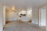 Located in Everett, WA, this single-floor, 2-bedroom, 2-bathroom residence offers a functional and comfortable layout. The living room serves as the heart of the home, featuring plush wall-to-wall carpeting, a classic tile-surround wood-burning fireplace, and a sliding glass door that opens to a private balcony overlooking lush greenery. A ceiling fan adds practical comfort to the space. The kitchen is positioned adjacent to the living area in a semi-open layout, separated by a half-wall breakfast bar. It features white cabinetry, light countertops, black appliances including a range, microwave, and refrigerator, and wood-look flooring that extends through both bathrooms. The primary bedroom offers a window with outdoor views and a baseboard heater, while the second bedroom provides a quiet, carpeted retreat. Both bathrooms are finished with white vanity cabinetry, light countertops, and wood-look flooring. The full bathroom includes a tub-shower combination, while the second bathroom features a compact, efficient layout. Neutral tones and clean white walls throughout create a bright, move-in-ready atmosphere across the entire residence.
