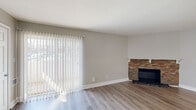 Located at 3630 Warwick Blvd in Kansas City's midtown area, this single-floor, 2-bedroom, 1-bathroom unit offers a practical and well-maintained layout. The living room serves as the centerpiece of the space, featuring warm wood-look luxury vinyl plank flooring, neutral gray walls, and a striking stacked-stone fireplace with a classic white mantle. A large sliding glass door with vertical blinds fills the room with natural light while providing outdoor access.

Both bedrooms continue the wood-look flooring and neutral color palette, creating a cohesive feel throughout. The primary bedroom is a comfortable size and includes a closet with sliding panel doors. The second bedroom features a built-in closet and a window that brings in natural light. Each room is served by a hallway that connects the unit's main areas efficiently.

The bathroom is well-appointed with warm beige tile surrounding a full tub-and-shower combination, accented by a decorative mosaic tile border. A marble-look tile floor, wooden vanity with a white countertop, and a window above the tub add both functionality and character. The kitchen, visible in the overview, features cabinetry and a practical layout. Overall, the unit presents a clean, updated aesthetic throughout.