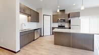 This single-floor unit at 202 Benson Ave SW in Willmar, Minnesota presents a modern, well-appointed layout designed for comfortable living. The kitchen serves as a central highlight, featuring dark wood-toned cabinetry, a subway tile backsplash, granite countertops, and a spacious island with pendant lighting overhead. Stainless steel appliances, including a range, microwave, dishwasher, and refrigerator, complete the space, which flows over light-toned luxury vinyl plank flooring.

The living areas offer recessed lighting, large windows that invite natural light, and a wall-mounted air conditioning unit. Bedrooms feature plush carpeting, ceiling fans, and generous built-in closets with wire shelving systems. Two bathrooms are present — one equipped with a walk-in shower and the other with a full soaking tub/shower combination — both finished with wood-toned vanities and granite countertops.

A dedicated in-unit laundry area accommodates a stacked washer and dryer and includes a window for natural ventilation. Throughout the unit, dark baseboards provide a clean contrast against neutral walls, contributing to a cohesive, contemporary aesthetic.