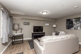 This two-floor residence offers a thoughtfully designed layout that balances comfort and functionality across its living spaces. The main level opens with a welcoming entryway leading into a spacious living room finished with warm hardwood-style flooring, neutral beige walls, and a textured ceiling. The living area comfortably accommodates a large sofa, accent chair, and entertainment center, creating an inviting atmosphere for relaxing or entertaining. A dining area sits adjacent, flowing naturally into the well-appointed kitchen, which features dark espresso cabinetry, black appliances including a gas range, dishwasher, and refrigerator, complemented by a double sink and ample counter space. Natural light filters in through multiple windows fitted with blinds throughout the home. The bathrooms are finished with tile flooring, dark vanity cabinetry, white countertops, and bright windows. A dedicated in-unit laundry room houses a full-size washer and dryer alongside utility storage. The bedrooms, located on the upper level, feature plush carpeting, generous natural light, and comfortable proportions ideal for rest and personalization. Together, the two floors offer a cohesive and practical living environment with consistent warm-toned finishes throughout.