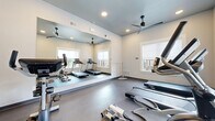 Located at 1828 Sandy Point Rd in Bryan, TX, this dedicated fitness center offers a well-appointed workout space designed to support a variety of exercise routines. The room features durable, low-maintenance flooring suited for high-traffic fitness use, complemented by neutral-toned walls and recessed lighting that create a clean, focused atmosphere.

A prominent floor-to-ceiling mirror spans one wall, effectively expanding the visual footprint of the space while allowing users to monitor their form during workouts. Ceiling fans ensure consistent air circulation throughout, contributing to a comfortable environment during exercise.

The fitness center is equipped with multiple cardio machines, including treadmills, stationary upright bikes, and elliptical trainers, as well as a rowing machine — providing a comprehensive range of cardiovascular training options. Several windows admit natural light and offer views of the surrounding outdoor areas, adding an open feel to the space.

Access is controlled via a dedicated entry door, and posted fitness center rules ensure proper use of the facility. The space is thoughtfully organized to maximize equipment capacity while maintaining clear circulation paths between machines. Overall, this fitness center delivers a practical and well-maintained environment for residents seeking convenient, on-site exercise amenities in Bryan, Texas.