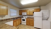 Located at 4121 Kimberly Parkway N in Columbus, Ohio, this single-floor residence offers a functional and comfortable layout throughout. The kitchen is well-appointed with warm oak cabinetry, dark laminate countertops, and a full suite of white appliances including a range, built-in microwave, refrigerator, and dishwasher. A stainless steel double sink and a window with a blind add practicality and natural light to the space. Notably, an in-unit stacked washer and dryer is conveniently located adjacent to the kitchen area, adding everyday convenience. The living area is generously sized, featuring neutral-toned carpet, a textured ceiling, and a sliding glass door that opens to an outdoor view, filling the room with natural light. The bedrooms are carpeted and well-proportioned, with one bedroom offering direct access to a bathroom, providing a private en-suite feel. The bathrooms are finished with tile flooring and oak vanities topped with dark laminate countertops. One bathroom features a stand-alone enclosed shower, while the other offers a full tub-shower combination. Throughout the residence, the neutral color palette and clean finishes create a bright, move-in-ready atmosphere.