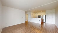 Located at 16605 Ash Way in Lynnwood, Washington, this one-bedroom, two-bathroom residence offers a thoughtfully designed single-floor layout with a clean, modern aesthetic throughout. The open-concept kitchen and living area serves as the heart of the home, featuring warm wood-look flooring, recessed lighting, and elegant pendant lights over a spacious island with quartz-style countertops. The kitchen is well-appointed with white upper cabinetry, wood-toned lower cabinets, a subway tile backsplash, and a full suite of stainless steel appliances including a range, microwave, and refrigerator. The living room is bright and airy, with large sliding glass doors opening to a private balcony that overlooks lush greenery, allowing natural light to fill the space. The bedroom offers plush carpeting, a closet, and a window framing outdoor views. Both bathrooms are finished with wood-look vinyl flooring, tub-shower combinations with tile surrounds, and warm neutral tones. A dedicated closet adds practical storage. The overall ambiance is light, fresh, and contemporary, with a cohesive palette of whites and natural wood tones creating a welcoming and functional living environment.