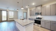 This well-designed 2-bedroom, 2-bathroom residence offers a thoughtful single-floor layout with contemporary finishes throughout. The open-concept kitchen and living area serves as the heart of the home, anchored by a spacious granite-topped island with an undermount sink and stylish pendant lighting. The kitchen is equipped with stainless steel appliances, including a refrigerator, range, and built-in microwave, complemented by sleek gray cabinetry and a herringbone-patterned tile backsplash. Wood-look flooring flows seamlessly throughout the entire residence, adding warmth and cohesion.

The primary bedroom is generously sized, featuring natural light from large windows, a ceiling fan, and direct access to a private balcony. The en-suite bathroom includes a dual-sink vanity with granite countertops, a soaking tub with tile surround, and a walk-in closet with built-in shelving. The second bedroom is bright and comfortable, benefiting from natural light and its own ceiling fan. A second full bathroom serves this room and guests. Two dedicated closets provide ample storage. The overall ambiance is clean, modern, and move-in ready.