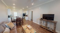 This single-story home offers a thoughtfully designed open-concept layout that seamlessly connects the living, dining, and kitchen areas. Crown molding, recessed lighting, and durable wood-look flooring run throughout, lending a cohesive and polished appearance to the interior.

The kitchen is well-equipped with white shaker-style cabinetry, granite countertops, stainless steel appliances including a range, microwave, and refrigerator, and a undermount sink positioned beneath a window that brings in natural light. A raised breakfast bar provides additional counter space and casual seating.

The adjoining living and dining area is generously sized, accommodating both a full dining table set and a comfortable living space with a ceiling fan overhead. Windows fitted with plantation-style blinds allow natural light while maintaining privacy.

The bedroom features crown molding, a ceiling fan, and wood-look flooring, offering a calm and comfortable retreat. The full bathroom includes a granite-topped vanity with white cabinetry and a tub-shower combination.

A dedicated laundry room with full-size washer and dryer hookups adds everyday convenience. The attached garage provides secure parking and additional storage space, completing this functional and well-finished home.
