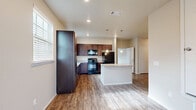 Located on 26th Street in Lubbock, Texas, this single-story, 2-bedroom, 2-bathroom home offers a well-organized layout designed for comfortable everyday living. The open-concept kitchen and living area form the heart of the home, featuring rich dark wood cabinetry, granite countertops, pendant lighting, and a central island that provides additional prep and dining space. Black appliances complement the kitchen's aesthetic, while large windows dressed with blinds allow natural light to brighten the space. Wood-look tile and laminate flooring run throughout the main living areas, adding warmth and easy maintenance. The spacious primary bedroom is generously sized, finished with soft carpeting and multiple windows that let in ample natural light. A dedicated closet provides practical storage. Both bathrooms continue the home's cohesive design with dark wood vanities, granite countertop surfaces, and wood-look flooring — one bathroom includes a full soaking tub. A ceiling fan in the living area enhances airflow and comfort. The home also includes an attached garage with a sectional door, offering secure parking and additional storage. Neutral wall tones throughout create a clean, inviting atmosphere well-suited to a variety of interior styles.
