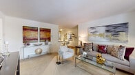 Located at 2509 Brush Rd in Schaumburg, Illinois, this single-floor residence offers a thoughtfully designed open layout that connects its key living spaces with ease. The living room is bright and welcoming, featuring plush carpeting, white walls that create a clean backdrop, and large windows that invite natural light and outdoor views of surrounding greenery. The space flows seamlessly into a dedicated dining area, which is distinguished by rich hardwood flooring, track lighting overhead, and built-in display shelving along the wall — ideal for everyday dining or entertaining guests. The kitchen is well-equipped with warm wood cabinetry, dark granite countertops, a tile backsplash, and stainless steel appliances, including a range and microwave. A pass-through opening connects the kitchen to the adjacent living and dining spaces, enhancing the open feel. A carpeted hallway with louvered closet doors leads to the bedroom, which offers generous closet space and a calm, neutral palette. The full bathroom features tile flooring, a tub-shower combination, and clean white fixtures. Throughout the residence, a cohesive design sensibility — combining neutral tones with modern finishes — creates a comfortable and functional living environment.