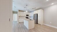 Located at 2116 Pleasant Road in Fort Mill, SC, this well-appointed single-story home offers four bedrooms, two bathrooms, a living room, and a dedicated laundry room across a comfortable and efficient layout. The open-concept kitchen serves as the heart of the home, showcasing white shaker cabinetry, granite-style countertops, a classic subway tile backsplash, and a full suite of stainless steel appliances. A center island with a built-in sink and pendant lighting adds both functionality and style, flowing seamlessly into the living area over light-toned hardwood-style flooring. The primary bedroom is generously sized, featuring plush carpeting, multiple windows that invite natural light, and a ceiling fan for added comfort. Additional bedrooms are finished with neutral tones and durable flooring, offering flexible use. The primary bathroom includes a double-sink vanity with undermount basins, stone-look tile flooring, and a tub-shower combination, while the second bathroom features a single vanity and a glass-enclosed shower. A dedicated laundry room with washer and dryer hookups and overhead shelving adds everyday convenience. Throughout the home, a consistent neutral color palette and clean, modern finishes create a bright and cohesive living environment.