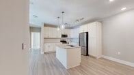 Located at 2116 Pleasant Road in Fort Mill, SC, this well-appointed single-story home offers four bedrooms, two bathrooms, a living room, and a dedicated laundry room across a comfortable and efficient layout. The open-concept kitchen serves as the heart of the home, showcasing white shaker cabinetry, granite-style countertops, a classic subway tile backsplash, and a full suite of stainless steel appliances. A center island with a built-in sink and pendant lighting adds both functionality and style, flowing seamlessly into the living area over light-toned hardwood-style flooring. The primary bedroom is generously sized, featuring plush carpeting, multiple windows that invite natural light, and a ceiling fan for added comfort. Additional bedrooms are finished with neutral tones and durable flooring, offering flexible use. The primary bathroom includes a double-sink vanity with undermount basins, stone-look tile flooring, and a tub-shower combination, while the second bathroom features a single vanity and a glass-enclosed shower. A dedicated laundry room with washer and dryer hookups and overhead shelving adds everyday convenience. Throughout the home, a consistent neutral color palette and clean, modern finishes create a bright and cohesive living environment.