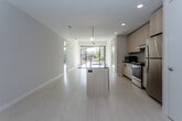 Located at 211 W Armour Blvd in Kansas City's vibrant Armour Hills neighborhood, this contemporary single-floor residence showcases a thoughtfully designed open-concept layout filled with natural light. The kitchen is a standout feature, equipped with light wood cabinetry, a dark-topped center island with an undermount sink, subway tile backsplash, stainless steel appliances, and stylish globe pendant lighting — all flowing seamlessly into the main living area. Large floor-to-ceiling sliding glass doors and expansive windows frame green tree canopy views, flooding the living spaces with sunlight and creating a bright, airy atmosphere. Light-toned flooring extends throughout the main living areas, contributing to a clean, modern aesthetic. A dedicated in-unit stacked washer and dryer adds everyday convenience. The bedroom features generous closet space with sliding frosted-glass panel doors and additional large windows with outdoor views. Two bathrooms are finished with marble-look quartz countertops, light wood vanities, dark hardware accents, large-format tile flooring, and walk-in glass-enclosed showers. Exposed concrete ceiling details in select areas add an industrial touch that complements the overall contemporary design sensibility.