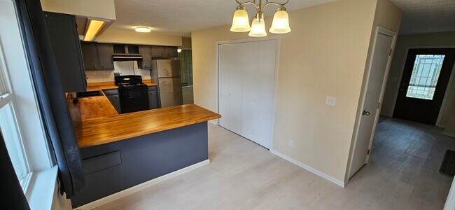 Cocina con vista a la sala familiar hacia el centro izquierda y la puerta principal a la derecha. - 578 Tyler St