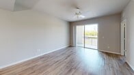Located at 3305 Grant Cove Circle in Cape Coral, Florida, this well-appointed one-bedroom, one-bathroom unit offers a thoughtfully designed single-floor layout. The open-concept living area seamlessly integrates the kitchen, dining, and living spaces, all finished with warm wood-look flooring that extends throughout the main areas. The kitchen is a standout feature, boasting rich dark-wood cabinetry reaching to the ceiling, granite countertops, a large center island with a built-in sink and pendant lighting overhead, and black appliances including a range, microwave, and refrigerator. Recessed lighting and pendant fixtures provide a bright, functional atmosphere. The living area is spacious and airy, benefiting from a ceiling fan and sliding glass doors that open onto a private balcony with outdoor views. The bedroom is carpeted for comfort, fitted with a ceiling fan, and features a large window that allows ample natural light. It includes access to a walk-in closet with wire shelving. The bathroom offers dual granite-topped vanities with dark cabinetry and wood-look flooring. Additional conveniences include a dedicated laundry area and two closets. The unit presents a clean, modern aesthetic with neutral tones throughout.
