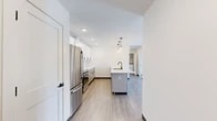 Located at 21 Loso Dr in Cicero, NY, this well-appointed 2-bedroom, 2-bathroom residence offers a thoughtfully designed single-floor layout. Light-toned luxury vinyl plank flooring flows throughout, lending a clean, cohesive look to every room.

The open-concept kitchen and living area serves as the heart of the home. The kitchen is outfitted with crisp white shaker cabinetry, a classic subway tile backsplash, quartz countertops, and a full suite of stainless steel appliances including a range, over-the-range microwave, and refrigerator. A central island with a built-in sink provides additional prep space and seating, illuminated by a trio of modern pendant lights.

The living area benefits from a sliding glass door that opens to a private outdoor balcony, filling the space with natural light and neighborhood views. The spacious primary bedroom features two large windows with abundant natural light, a ceiling fan, and access to a generous walk-in closet with extensive rod and shelf storage. The second bedroom is equally well-sized with neutral finishes. Both bathrooms are tastefully appointed; one includes a soaking tub with large-format white tile surround and matte black fixtures complemented by granite countertops. A dedicated hallway connects all rooms, completing this functional and modern layout.