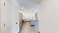 Located at 21 Loso Dr in Cicero, NY, this well-appointed 2-bedroom, 2-bathroom residence offers a thoughtfully designed single-floor layout. Light-toned luxury vinyl plank flooring flows throughout, lending a clean, cohesive look to every room.

The open-concept kitchen and living area serves as the heart of the home. The kitchen is outfitted with crisp white shaker cabinetry, a classic subway tile backsplash, quartz countertops, and a full suite of stainless steel appliances including a range, over-the-range microwave, and refrigerator. A central island with a built-in sink provides additional prep space and seating, illuminated by a trio of modern pendant lights.

The living area benefits from a sliding glass door that opens to a private outdoor balcony, filling the space with natural light and neighborhood views. The spacious primary bedroom features two large windows with abundant natural light, a ceiling fan, and access to a generous walk-in closet with extensive rod and shelf storage. The second bedroom is equally well-sized with neutral finishes. Both bathrooms are tastefully appointed; one includes a soaking tub with large-format white tile surround and matte black fixtures complemented by granite countertops. A dedicated hallway connects all rooms, completing this functional and modern layout.
