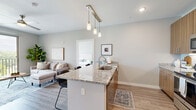 Located at 1436 S Green St in Sheboygan, WI, this well-appointed 2-bedroom, 2-bathroom unit offers a thoughtfully designed single-floor layout that balances comfort and modern style. The open-concept kitchen and living area serves as the heart of the home, featuring warm wood-toned cabinetry that extends to the ceiling for ample storage, granite countertops, a central island with pendant lighting and bar seating, and a full suite of stainless steel appliances. Light wood-tone flooring flows throughout, complementing the neutral color palette and recessed lighting. The living room is bright and inviting, highlighted by a large sliding glass door that opens onto a private balcony with outdoor views, allowing abundant natural light to fill the space. The primary bedroom is generously sized, with a wide window framing outdoor views, a ceiling fan, and access to a dedicated walk-in closet outfitted with wire shelving. The second bedroom also enjoys natural light through its own window. Both bathrooms are clean and functional, with one featuring a glass-enclosed walk-in shower. The overall ambiance is contemporary and fresh, offering a comfortable, move-in-ready living experience in a well-maintained building.
