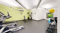 Located at 1862 E 123rd St in Cleveland, Ohio, this dedicated fitness center offers a well-appointed, single-floor exercise room designed to support a comprehensive workout experience. The space features a clean, modern aesthetic with crisp white ceilings and walls accented by a vibrant lime-green feature wall, adding an energizing atmosphere reinforced by motivational wall decals.

Overhead linear LED lighting ensures the room is brightly and evenly illuminated throughout. The durable speckled rubber flooring provides excellent traction and cushioning, ideal for a wide range of physical activities. A wall-mounted split air conditioning unit maintains a comfortable climate year-round.

The cardio zone is well-equipped with a treadmill, elliptical trainer, and stationary bike, all Spirit-brand machines, alongside a wall-mounted flat-screen television for entertainment during workouts. The strength training area includes a multi-function cable machine, an adjustable weight bench, and a tiered dumbbell rack stocked with a range of free weights. A dedicated functional fitness corner houses a ball rack with stability and medicine balls in various sizes, resistance bands, exercise mats, and additional accessories. The space is efficiently organized to maximize usability while maintaining comfortable room to move freely between stations.