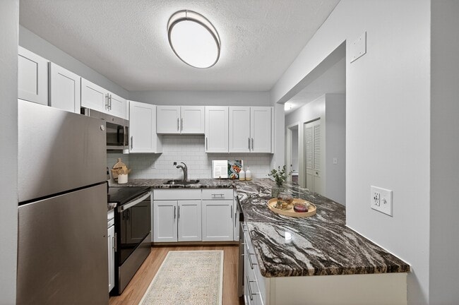 Elevate your lifestyle at Park Village West with this modern kitchen featuring sleek stainless steel appliances and elegant granite countertops. Designed for both style and functionality, it's perfect for culinary creativity. Schedule a tour today! - Park Village West