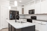 Located at 2701 Seabiscuit Ln in Greensboro, NC, this single-floor home offers a thoughtfully designed layout with contemporary finishes and a cohesive neutral color scheme. The kitchen serves as a standout centerpiece, showcasing crisp white cabinetry that extends to the ceiling, a classic subway tile backsplash, and a bold navy blue island topped with light marble-style countertops and an undermount sink. Pendant lighting illuminates the island, while recessed ceiling lights and black appliances, including a French door refrigerator and range, complete the functional space. A built-in wine rack and glass-front upper cabinets add refined detail.

Living and dining areas feature wood-look flooring in a warm gray tone, crown molding, and generous natural light from windows fitted with horizontal blinds. Bedroom spaces are finished with plush neutral carpet, ceiling fans, and ample natural light. The bathroom features white cabinetry paired with dark granite countertops, an undermount sink, and brushed nickel fixtures, lending a polished contrast. Paneled interior doors with brushed hardware are consistent throughout, contributing to the home's clean, modern aesthetic. Overall, the space presents a well-balanced combination of style and practicality.