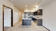Located in Arlington, WA, this well-designed one-bedroom, one-bathroom residence offers a thoughtful layout across a single floor. The open-concept living, dining, and kitchen area forms the heart of the home, featuring light wood-look flooring and recessed lighting throughout. The kitchen is a standout, outfitted with dark espresso cabinetry, quartz countertops, a subway tile backsplash, a center island, and a full suite of stainless steel appliances including a refrigerator, range, microwave, and dishwasher. A dedicated entrance leads seamlessly into this bright, connected living space. The bedroom offers plush carpeting, natural light through a window with outdoor views, and access to a generously sized walk-in closet with wire shelving for ample storage. A second closet provides additional organization options. The combined bathroom and laundry room features light flooring, a dark vanity with quartz countertops, and a grab bar for added accessibility. A private balcony extends the living space outdoors. Clean neutral tones, modern finishes, and a practical floor plan make this residence a comfortable and functional home.