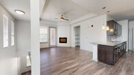 This thoughtfully designed 1-bedroom, 2-bathroom residence offers a functional and modern living experience across a single floor. The open-concept living and kitchen area serves as the heart of the home, anchored by warm wood-look flooring, a ceiling fan, and a sleek built-in fireplace flanked by open shelving. Natural light flows in through multiple windows fitted with blinds, creating a bright and welcoming atmosphere. A kitchen bar with pendant lighting connects the kitchen seamlessly to the living space.

The galley-style kitchen is a standout feature, boasting dark espresso cabinetry, granite countertops, a grey subway tile backsplash, and black stainless steel appliances, all complemented by the continuous wood-look flooring.

The bedroom is a comfortable retreat featuring plush carpeting, a tray ceiling, and a window with outdoor views. Both bathrooms are finished with wood-look tile flooring and dark vanity cabinetry with brushed nickel fixtures. One bathroom includes a soaking tub surrounded by large-format neutral stone-look tile, adding a spa-like touch.

Additional conveniences include a dedicated laundry area with an in-unit washer and dryer, a hallway closet for storage, and carpeted stairs leading to the unit's private entrance. The overall aesthetic is clean, contemporary, and move-in ready.