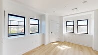 Located at 4124 Parkside Avenue in Philadelphia's vibrant West Philadelphia neighborhood, this thoughtfully designed studio unit offers a clean, modern aesthetic throughout. The open-concept layout is anchored by light-toned hardwood flooring that extends seamlessly across the entire space, complementing the crisp white walls and creating a bright, airy atmosphere.

The kitchen is a standout feature, outfitted with a two-tone cabinet design pairing light wood upper cabinets with sleek navy lower cabinets, white subway tile backsplash, a matte black pull-down faucet, and stainless steel appliances including an electric range and over-the-range microwave. The clean countertops and efficient L-shaped layout make the most of the available space.

Multiple black-framed windows flood the unit with natural light while offering pleasant views of surrounding tree canopy, giving the space a refreshing connection to the outdoors. The entry area is highly functional, featuring an in-unit stacked washer and dryer alongside additional storage access — a rare and convenient amenity. Modern hardware and matte black accents are consistent throughout, tying the design together cohesively. This unit offers a well-appointed, move-in-ready living environment with contemporary finishes at every turn.