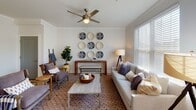 This thoughtfully designed single-floor residence offers a cohesive blend of modern finishes and comfortable living spaces throughout. The living room serves as a welcoming centerpiece, featuring crown molding, a ceiling fan, light wood-style flooring, and generous natural light streaming through large windows fitted with wood blinds. Decorative wall art and a warm, layered aesthetic give the space a curated, inviting feel.

The dining area adjoins the living space and benefits from additional natural light, with direct access to the outdoors through a glass-paneled door — ideal for easy indoor-outdoor flow. The kitchen is outfitted with stainless steel appliances, including a French door refrigerator, electric range, and over-the-range microwave, complemented by gray shaker-style cabinetry and clean white countertops. A stacked in-unit washer and dryer is conveniently located just off the kitchen.

The residence includes multiple bedrooms, each finished with plush carpeting, ceiling fans, and ample natural light. The primary bedroom features a walk-in closet and an en-suite bathroom with a gray vanity, white countertop, and wood-style flooring. A second full bathroom offers a tub-shower combination with tiled surround. Throughout the home, neutral tones and consistent finishes create a calm, harmonious ambiance.