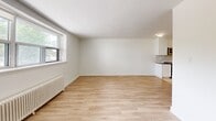 Located at 2220 Weston Road in Toronto's Weston neighbourhood, this 2-bedroom, 1-bathroom unit offers a clean, modern aesthetic across a well-proportioned single-floor layout. The open living area is bright and welcoming, featuring warm light wood laminate flooring, crisp white walls, and natural light streaming through a large window. A classic cast iron radiator adds a charming heritage touch to the space.

The kitchen is a standout feature, thoughtfully renovated with full-height white shaker cabinetry, a herringbone tile backsplash, dark quartz countertops, a double stainless steel sink, and recessed lighting. Tile flooring grounds the space and complements the clean, functional design.

The primary bedroom is a comfortable, well-sized retreat featuring its own large window with neighbourhood views and a cast iron radiator. The second bedroom is similarly bright, with a window and radiator, making it suitable as a guest room, office, or additional sleeping space.

The bathroom is finished in all-white subway tile, complete with a modern undermount sink, white vanity, a tiled shower area with a handheld fixture, and bright overhead lighting, creating a clean, spa-like atmosphere.

Overall, this unit presents a cohesive, freshly updated interior with a neutral palette ideal for a variety of living arrangements.