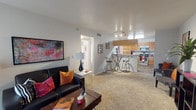 This single-story residence offers a thoughtfully arranged floor plan that maximizes functionality across its living spaces. The open-concept living area is finished with wall-to-wall carpet and features a large sliding glass door fitted with vertical blinds, allowing natural light to fill the room while providing direct access to a private patio with outdoor views. The living space flows seamlessly into the kitchen, which is defined by a raised bar counter with seating, warm wood-grain cabinetry, granite-style countertops, and stainless steel appliances including an electric range and microwave. Track lighting overhead adds a modern touch to the kitchen area.

The two bedrooms are each carpeted and equipped with ceiling fans, offering a comfortable and well-lit environment. Both rooms include sliding-door closets with built-in shelving, providing ample storage. One bedroom benefits from additional natural light through a side window with vertical blinds.

The bathroom features wood-look plank flooring, a warm wood-toned vanity with a granite-style countertop, a framed mirror, and a shower-tub combination. Throughout the residence, the neutral color palette and consistent design elements create a cohesive and practical living environment.