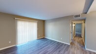 This single-floor residence offers a clean, contemporary layout with consistent modern finishes throughout. The main living area is spacious and open, featuring wood-look laminate flooring, neutral-toned walls, and large vertical blinds covering a sliding door that allows abundant natural light to fill the room. The space flows naturally through a hallway connecting the various rooms.

The kitchen has been thoughtfully updated with white shaker-style cabinetry, quartz countertops featuring subtle veining, a classic subway tile backsplash, and a full suite of stainless steel appliances including a range, over-the-range microwave, refrigerator, and dishwasher. A double stainless steel sink adds both functionality and style.

The bedrooms continue the wood-look flooring theme and are finished with the same warm neutral palette. One bedroom features an exposed brick accent wall and a window with horizontal blinds, adding a distinctive textural element to the space.

The bathrooms are finished with white vanities topped with quartz countertops, undermount sinks, brushed nickel fixtures, and framed mirrors. One bathroom includes a full tub-shower combination with white tile surround. Throughout the unit, clean white baseboards and trim provide a crisp contrast to the warm wall tones, contributing to the overall fresh and move-in-ready ambiance.