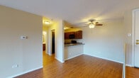 Located at 101 Busse Rd in Elk Grove Village, Illinois, this single-floor unit offers a well-organized and functional layout designed for comfortable everyday living. The open-concept living and dining area is bright and spacious, showcasing warm hardwood-style flooring throughout and a ceiling fan that enhances the airy feel of the space. A sliding glass door floods the living area with natural light and provides direct access to a private balcony with outdoor views, complemented by baseboard heating along the perimeter walls. The kitchen is thoughtfully designed with rich dark wood cabinetry, dark granite-style countertops, and a peninsula with a built-in sink that opens toward the living area — ideal for casual dining or entertaining. Black appliances, including a refrigerator, microwave, and range, complete the kitchen's cohesive aesthetic. A hallway connects the main living space to the additional rooms, including a carpeted bedroom that features a window with natural views and baseboard heating. The bathroom is fitted with a full soaking tub and shower combination, a toilet, and hardwood-style flooring, maintaining a clean and neutral palette. The unit's entry features a raised step foyer, adding a subtle architectural detail to the overall design.