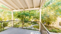 Located at 200-204 W Rowland St in Covina, CA, this single-floor unit offers a well-organized layout with a clean, functional design throughout. The living area is a standout feature, showcasing rich, dark hardwood flooring that flows seamlessly through the main living spaces. Large sliding glass doors open directly onto a covered balcony, flooding the room with natural light and providing picturesque views of mature, lush greenery — creating a serene indoor-outdoor connection.

The kitchen is efficiently designed with white cabinetry, light-toned countertops, a double-basin stainless steel sink, and a gas range, offering ample storage and prep space. Hardwood flooring continues into the kitchen, maintaining a cohesive aesthetic.

The bedroom features plush carpeting, a wall-mounted air conditioning unit, and a window that looks out onto the surrounding greenery, providing both comfort and natural light. The bathroom is clean and straightforward, appointed with a single-sink vanity with cabinet storage, a medicine cabinet mirror, and accessibility grab bars, reflecting a practical and inclusive design.

A covered balcony with a metal railing completes the unit, offering a peaceful outdoor retreat surrounded by tree canopy — an inviting extension of the living space.