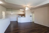 Located in Las Cruces, NM, this single-floor home offers a well-designed open-concept layout that seamlessly connects the living area and kitchen. Rich, dark hardwood-style flooring extends throughout the main living spaces, creating a warm and cohesive aesthetic. The kitchen features warm-toned wood cabinetry, a full suite of appliances including a range, refrigerator, and built-in microwave, and is anchored by a peninsula-style breakfast bar that opens into the living area. Vaulted ceilings in the kitchen and main living space add a sense of height and volume, enhancing the open feel of the home. A pass-through window detail in the living area adds architectural character. The bedrooms are finished with plush carpeting, crown molding, and ceiling fans, and each receives natural light through slatted windows with views of surrounding greenery. The bathrooms are appointed with tile flooring, warm wood vanity cabinetry with ample counter space, framed mirrors, and a tub-shower combination. The overall ambiance of the home is practical yet comfortable, with a neutral color palette throughout that lends itself well to a variety of furnishing styles.