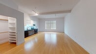 Located on Chandler Boulevard in North Hollywood, this single-floor unit presents a contemporary open-concept design that seamlessly integrates the living and kitchen areas. Polished light bamboo hardwood flooring extends throughout the main living space, reflecting natural light that enters through a large window dressed with horizontal blinds, creating a bright and airy atmosphere.

The kitchen is thoughtfully designed with a galley-style layout featuring high-gloss white upper cabinetry contrasted by dark lower cabinets and black countertops. A luminous tiled backsplash in a soft teal hue adds a distinctive visual element. Stainless steel appliances, including a refrigerator, microwave, and gas range, complete this functional and modern cooking space.

The living area is generously proportioned, offering flexible use of space, while a walk-in closet provides ample built-in shelving and storage. A stacked washer and dryer unit is conveniently located within the unit. The bathroom features dark penny-round tile flooring, a black-framed vanity with an illuminated mirror, and a window that allows natural light to filter in. Track lighting in the main area adds to the clean, modern aesthetic throughout.