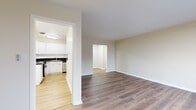 This 1-bedroom, 1-bathroom unit is laid out on a single floor, offering a practical and comfortable living arrangement. The interior is unified by warm hardwood-style flooring that extends throughout the main living areas, bedroom, and hallways, creating a cohesive and clean aesthetic. Neutral beige wall tones complement the light-toned trim and white ceilings, lending a bright and welcoming ambiance throughout.

The living room is generously sized, featuring a ceiling fan, a large window that allows natural light to fill the space, and a baseboard radiator for heating. The open layout provides ample room for flexible furniture arrangements. The kitchen is efficiently designed with white cabinetry, dark granite-style countertops, and a black electric range with oven. A dishwasher and sink with a window above complete the functional workspace.

The bedroom offers a comfortable footprint with a double-door closet for storage, hardwood-style flooring, and warm neutral walls. The full bathroom includes a white vanity with a marble-style countertop, brushed nickel fixtures, a framed mirror, and a full-size soaking tub with a tiled surround. The unit also includes a dedicated laundry area, adding everyday convenience. Two hallways provide smooth circulation throughout the space.