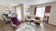 This single-floor residence offers a thoughtfully arranged layout with a cohesive neutral color palette accented by warm tones throughout. The living room serves as the centerpiece of the home, featuring rich hardwood-style flooring, a fireplace framed by a clean white mantle, and windows dressed with deep mauve curtains that allow natural light to filter in. A sliding glass door connects the dining area to an outdoor balcony, making the space feel open and connected to the exterior. The dining area is defined by a pendant light fixture overhead and provides a welcoming setting for meals.

The kitchen is well-equipped with white cabinetry, granite countertops, a subway tile backsplash, and stainless steel appliances, offering both style and functionality. The bedroom is a quiet retreat with plush wall-to-wall carpeting, a textured ceiling, and a window that brings in soft natural light. Wall-mounted sconces and tasteful artwork contribute to the room's calm atmosphere.

The bathroom features granite countertop vanity with a framed mirror, tiled tub-shower combination, and wood-style flooring. Throughout the home, textured ceilings and clean white trim provide a consistent architectural finish that ties each room together cohesively.
