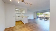 Located at 7955 Magnolia Ave in Riverside, California, this two-bedroom, two-bathroom residence offers a practical and well-organized single-floor layout. The open-concept living and kitchen area serves as the heart of the home, where light wood-style flooring flows throughout. The kitchen features white cabinetry extending to the ceiling for ample storage, light countertops, a skylight for added natural brightness, white appliances, and a peninsula that provides a natural divide between the kitchen and living space. A rail lighting fixture accents the kitchen and dining area. The living room is bright and airy, benefiting from large sliding glass doors that open to a private outdoor patio, framing views of surrounding greenery. Both bedrooms are carpeted and receive natural light through wide sliding windows overlooking the exterior. The primary bedroom includes a dedicated walk-in closet with built-in shelving. The bathrooms are finished in a clean, neutral palette, with one featuring a wide vanity with white cabinetry, a large mirror, and wood-style flooring. A textured ceiling is consistent throughout the residence, contributing to its classic character. The overall ambiance is clean, bright, and functional.