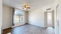 Located in Mesa, Arizona, this 2-bedroom, 2-bathroom single-story home offers a well-designed layout with a thoughtful mix of modern updates and functional living spaces. The living room serves as a central gathering area, highlighted by a classic fireplace and a striking arched window that fills the space with natural light. Wood-style flooring runs throughout the main living areas, adding warmth and continuity.

The kitchen is a standout feature, showcasing gray cabinetry, white subway tile backsplash, light quartz countertops, and a peninsula that provides additional workspace and casual seating. Stainless steel appliances, including a refrigerator, range, and microwave, complete the modern aesthetic.

Both bedrooms are carpeted for comfort and include sliding-door closets and ceiling fans. The primary bedroom features a sliding glass door with outdoor views, while the second bedroom benefits from natural light through a large window. A hallway bathroom with a white vanity and tub/shower combination serves the bedrooms conveniently.

Built-in shelving in the living area adds practical storage and display space. The textured ceilings and neutral color palette throughout create a clean, cohesive atmosphere suited to a variety of interior styles.
