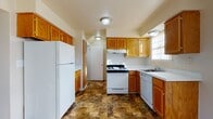 Located at 1903 N Perry St in Pontiac, Michigan, this three-floor home offers a practical and well-organized layout across its levels. The kitchen is a standout feature, equipped with warm oak cabinetry, white appliances including a gas range, dishwasher, and full-size refrigerator, complemented by white countertops and stone-patterned tile flooring. A sliding glass door in the kitchen area provides direct outdoor access and fills the space with natural light, offering views of the surrounding neighborhood. The living areas and bedrooms feature neutral-toned carpeting, creating a comfortable and cohesive feel throughout. Windows fitted with vertical blinds allow ample natural light into each room. The home includes multiple bathrooms, each finished with the same stone-patterned tile flooring as the kitchen, oak vanity cabinetry, and white fixtures. One bathroom features a tiled tub surround, while another serves as a convenient half bath. The basement level presents an open, unfinished space with a painted concrete floor and exposed ceiling joists, offering significant potential for storage or future customization. Overall, the home provides a clean, functional environment with consistent finishes throughout its three floors.