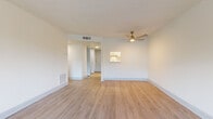 Located at 208 47th Ave N in Saint Petersburg, Florida, this single-story unit offers a clean, updated interior with a cohesive, light-toned aesthetic throughout. The living area is generously sized, featuring light wood-style laminate flooring, crisp white walls, and a modern gold-accented ceiling fan. A large window allows natural light to fill the space and provides views of the surrounding greenery, contributing to an open and airy atmosphere. Visible HVAC vents indicate central air conditioning throughout.

The galley-style kitchen is efficiently designed with white cabinetry featuring brushed metal hardware, white subway tile backsplash, and light countertops. Stainless steel appliances include an electric range, over-the-range microwave, refrigerator, and dishwasher. A skylight above the kitchen enhances natural brightness in the space.

The bedroom is well-proportioned with the same light flooring found throughout the unit and includes access to a walk-in closet with built-in shelving. The bathroom features a full tub-shower combo with white square tile surround, wood-style flooring, and a clean, functional layout. Overall, the unit presents a bright, updated living environment with practical finishes and a neutral palette.