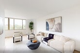 Located at 99 Gorge Rd in Edgewater, NJ, this well-appointed two-bedroom, one-bathroom residence offers a thoughtfully designed single-floor layout with a clean, modern aesthetic throughout. Light hardwood flooring flows seamlessly across the living, dining, and bedroom areas, creating a cohesive and inviting atmosphere.

The open living and dining area is bathed in natural light from large windows overlooking lush greenery, with the living room featuring a wall-mounted TV, contemporary furnishings, and a geometric coffee table. The adjacent dining space is elevated by a striking brass sputnik chandelier and a round dark wood table set beneath a large window with outdoor views.

The galley-style kitchen is efficiently designed with white shaker cabinetry, white quartz countertops, a subway tile backsplash, and a full suite of stainless steel appliances including a refrigerator, range, microwave, and dishwasher.

Both bedrooms are bright and serene, each featuring large windows with verdant views, hardwood floors, and a calm neutral palette. The primary bedroom includes a wall-mounted TV and a cozy accent chair.

The bathroom is finished with warm stone tile floors, a tub-shower combo with stone surround, a mid-century walnut vanity, and recessed lighting. A clean hallway connects the private areas of the residence, completing this well-organized and stylish home.