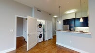 Located at 6138 Franklin Ave in the heart of Hollywood, Los Angeles, this contemporary single-floor residence combines modern design with functional living. Warm hardwood flooring flows consistently throughout the space, creating a cohesive and inviting atmosphere.

The open-concept kitchen is a standout feature, outfitted with bold dark cabinetry, stainless steel appliances including a refrigerator, gas range, and microwave, and a classic white subway tile backsplash. A peninsula counter with pendant lighting above serves as both a food prep area and a casual dining space, seamlessly connecting the kitchen to the living area.

The living and bedroom spaces are bathed in natural light, with large windows and French doors topped by transom windows that invite an abundance of sunshine. A ceiling fan adds comfort to one of the bedrooms, while neutral gray walls throughout provide a clean, modern backdrop.

A dedicated in-unit laundry closet with a stacked washer and dryer offers added convenience. The bathroom is finished with crisp white tile surrounds, a soaking tub, and polished chrome fixtures, delivering a clean and modern aesthetic. This well-appointed residence offers a comfortable and stylish urban lifestyle in a prime Los Angeles location.