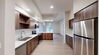 Located at 6914 NE 126th St in Vancouver, WA, this thoughtfully designed single-floor home offers 3 bedrooms, 3 bathrooms, a den, and generous living space throughout. Light wood-tone flooring flows consistently across the entire layout, creating a cohesive and clean aesthetic.

The open-concept kitchen, dining, and living area serves as the heart of the home. The kitchen is equipped with rich walnut-toned cabinetry, white quartz countertops, subway tile backsplash, stainless steel appliances including a refrigerator and range, and a peninsula with pendant lighting. A wall-mounted mini-split unit provides efficient climate control. The living area opens directly to a patio via sliding glass doors, bringing in natural light and outdoor views.

The spacious primary bedroom features a second patio access point through sliding doors, along with two windows that invite natural light. Its en-suite bathroom includes a dual-sink vanity with gray cabinetry and a large mirror. Additional bathrooms feature tub-shower combinations with brushed nickel fixtures. Closets throughout include wire shelving systems for organized storage.

The den offers a versatile flex space, while the dedicated laundry room and well-connected hallway add to the home's functional layout. Recessed lighting and a neutral color palette complete the modern, move-in-ready interior.