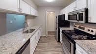 Located at 9991 Arbor Montgomery Ln in Cincinnati, OH 45249, this single-floor unit offers a well-designed layout with clean, contemporary finishes throughout. The kitchen is a standout feature, equipped with crisp white cabinetry, granite countertops, a tile backsplash, stainless steel appliances including a built-in microwave, and wood-look flooring that adds warmth and durability. A peninsula counter connects the kitchen to the dining and living areas, creating an open, cohesive flow. The living and dining spaces are finished with neutral gray walls and plush carpeting, complemented by a ceiling fan and a pendant light fixture. Natural light filters in through blinds-fitted windows, and the entryway features a classic paneled door with a hardwood-style tile entry mat. The bedrooms are generously sized with soft carpeting, gray walls, and windows that bring in natural light. One bedroom includes a louvered bifold closet door for ample storage. The bathroom is well-appointed with white cabinetry, granite countertops, a framed mirror, and wood-look plank flooring, with convenient access to the adjacent bedroom. Overall, the unit presents a polished, move-in-ready aesthetic with consistent finishes across all spaces.